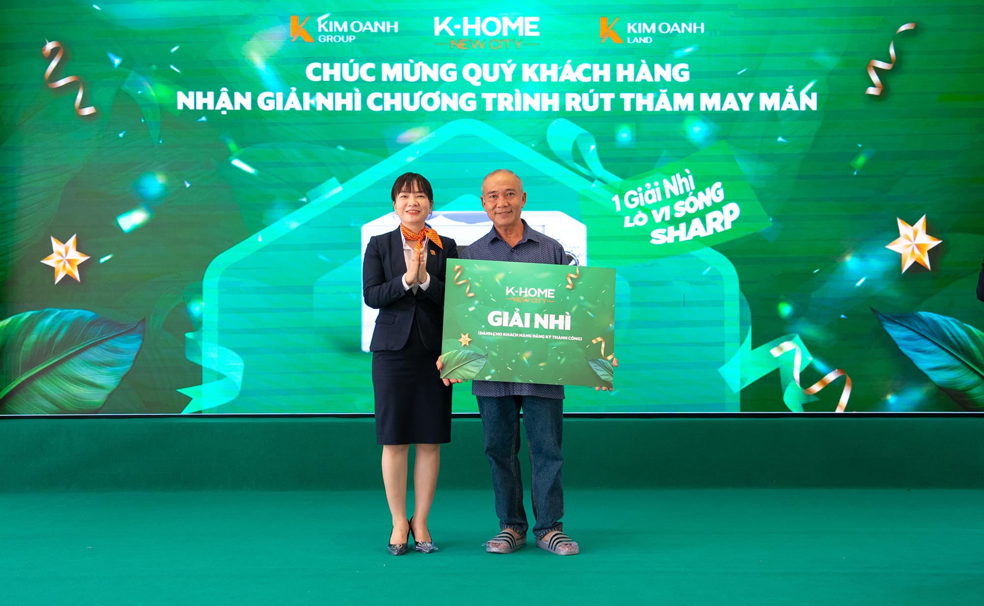 Bà Lê Thị Hạnh – Giám đốc Chi nhánh Thành Phố Mới trao tặng khách hàng may mắn trúng giải Nhì là 1 lò vi sóng SHARP của chương trình rút thăm trúng thưởng dành cho khách hàng đăng ký dịch vụ thành công